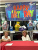 Volunteers Sit in Front of Prize Baskets