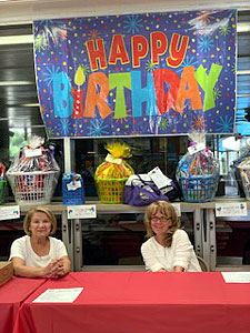 Volunteers Sit in Front of Prize Baskets